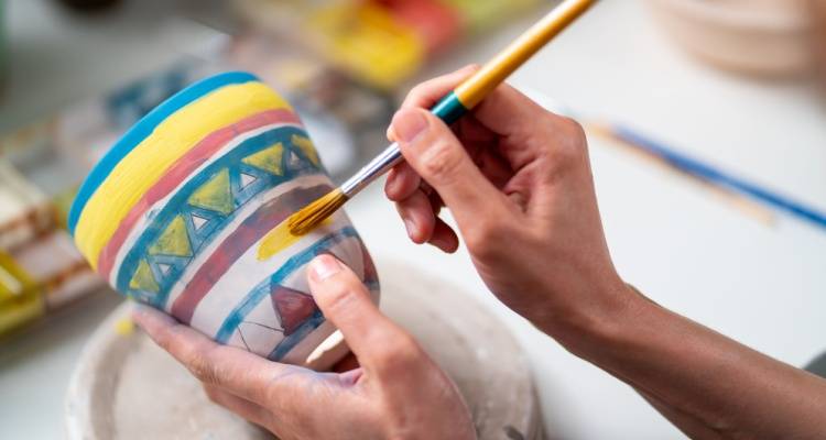 person painting ceramic bowl