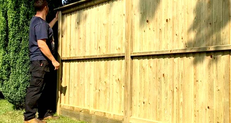 workman checking a garden fence installation