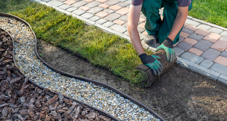 tradesperson laying new turf next to a garden path