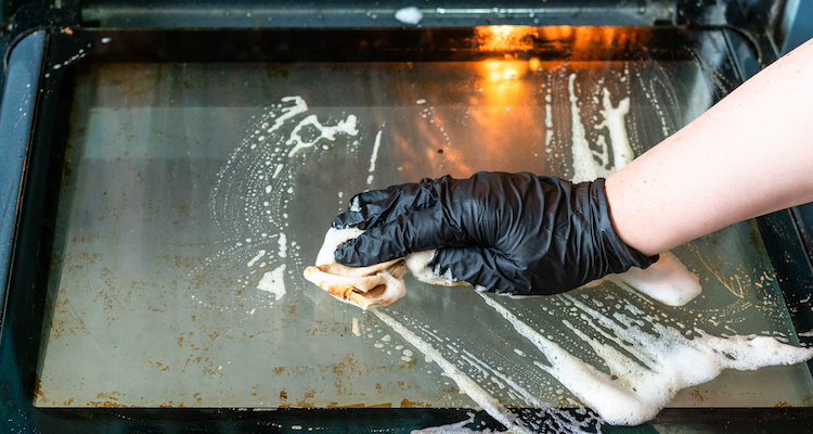 dirty oven door being cleaned by a professional oven cleaner